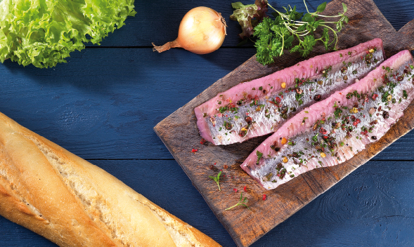 marinierte Heringsfilets auf Holzbrett mit Baguette und Gemü