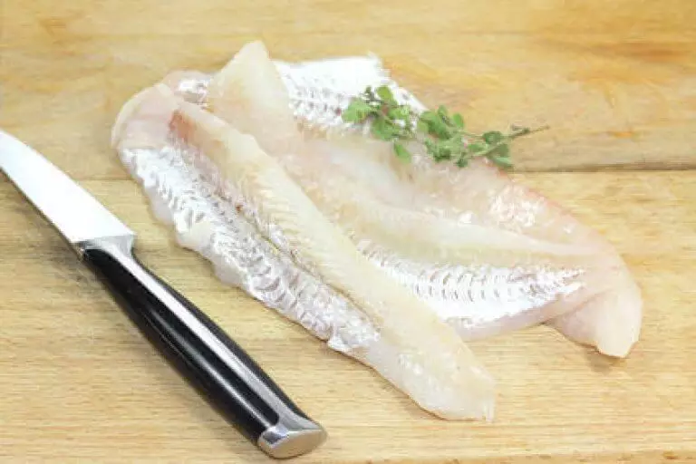 rohes Seelachsfilet ohne Haut auf Holzbrett mit Messer