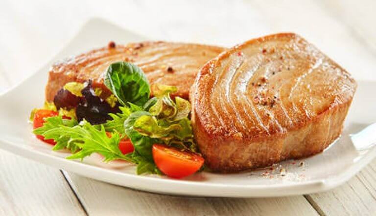 gebratenes Thunfischsteak mit Salat und Tomaten auf Teller