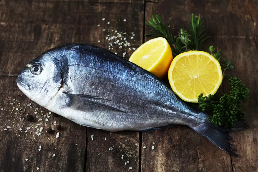 frische Dorade mit Zitrone und Kräutern auf Holzbrett