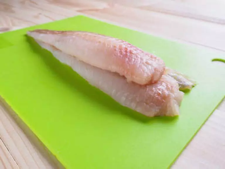 Rohes Rotbarschfilet auf grünem Schneidebrett