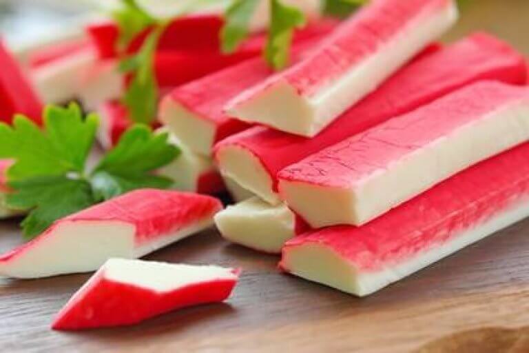 rote Surimi-Sticks auf Holzbrett mit Petersilie