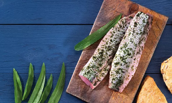 zwei rohe Lachsfilets mit Kräutern auf Holzbrett