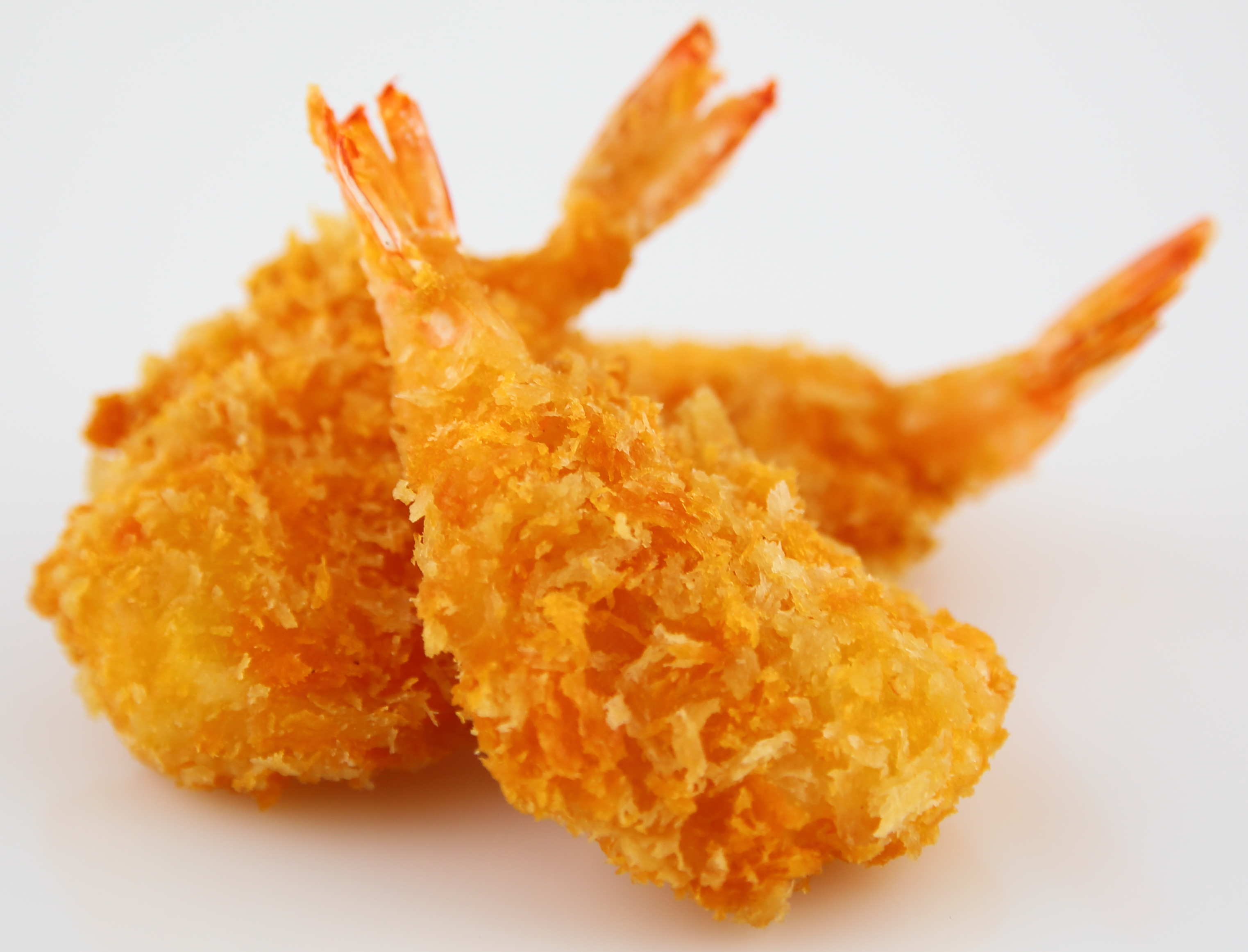 Drei goldbraun frittierte, panierte Garnelen auf weißem Hintergrund