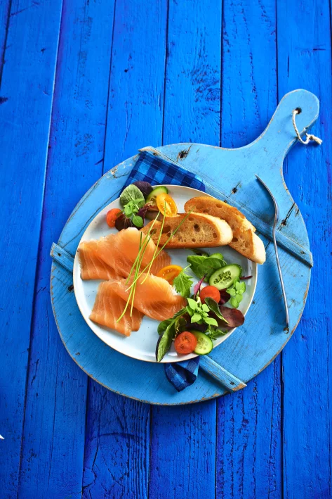 Räucherlachs, Baguette und Salat auf weißem Teller