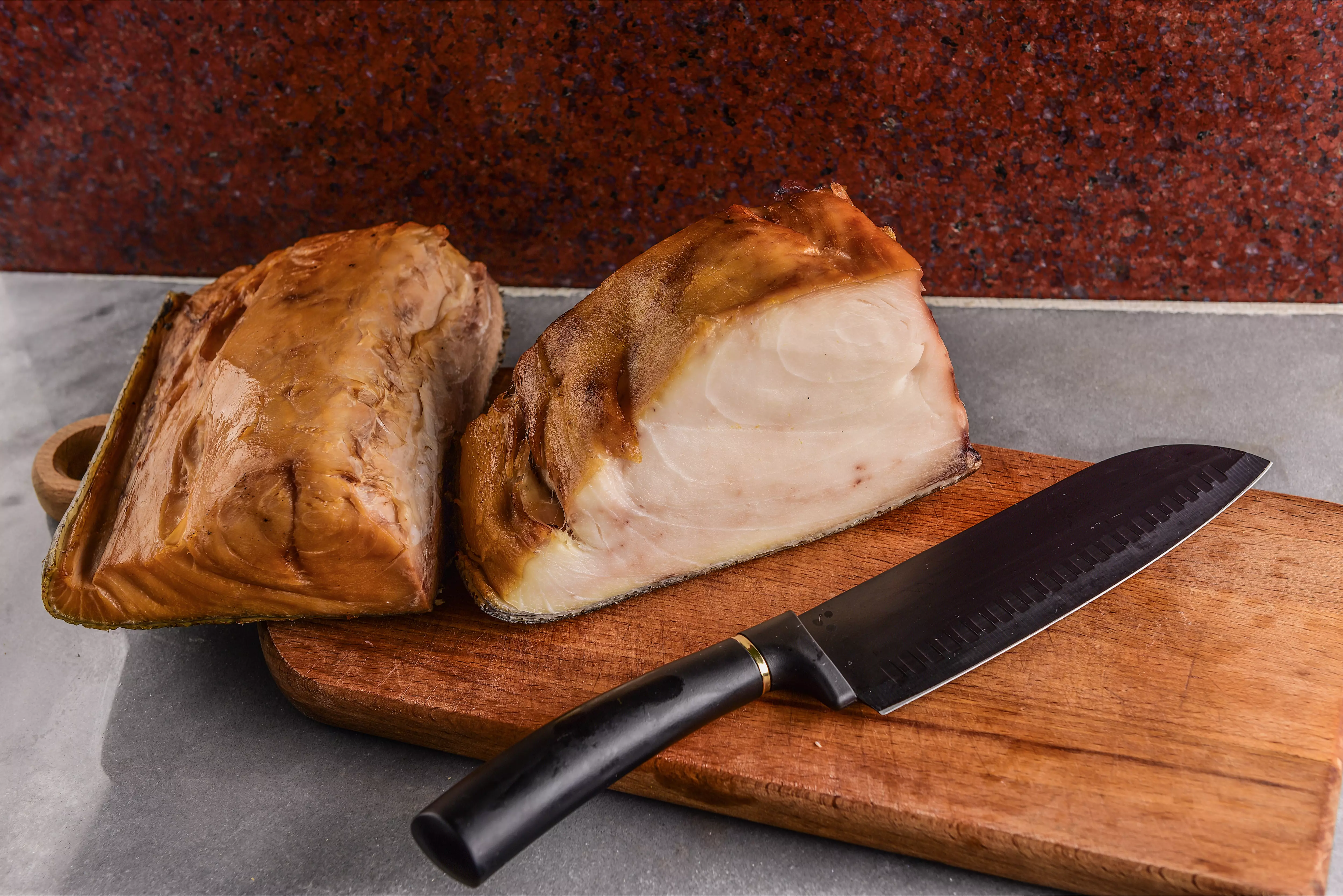 Zwei Stücke Räucherfisch auf Schneidebrett mit Messer