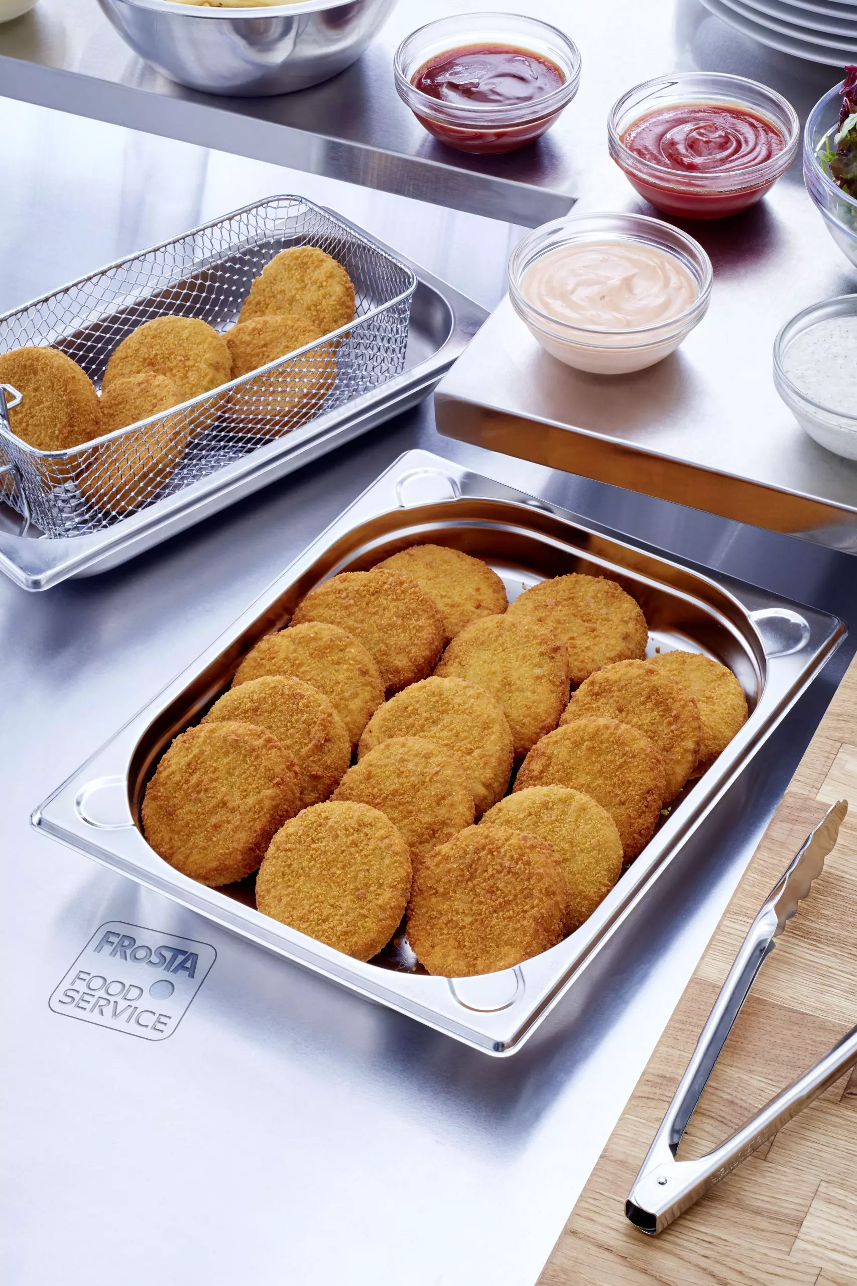 mehrere goldbraune Gemüsefrikadellen in Edelstahlbehälter