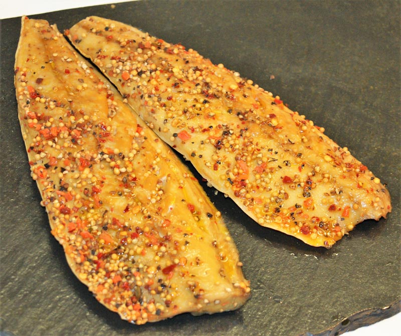 Zwei mit Gewürzen bedeckte Fischfilets auf einer dunklen Schieferplatte