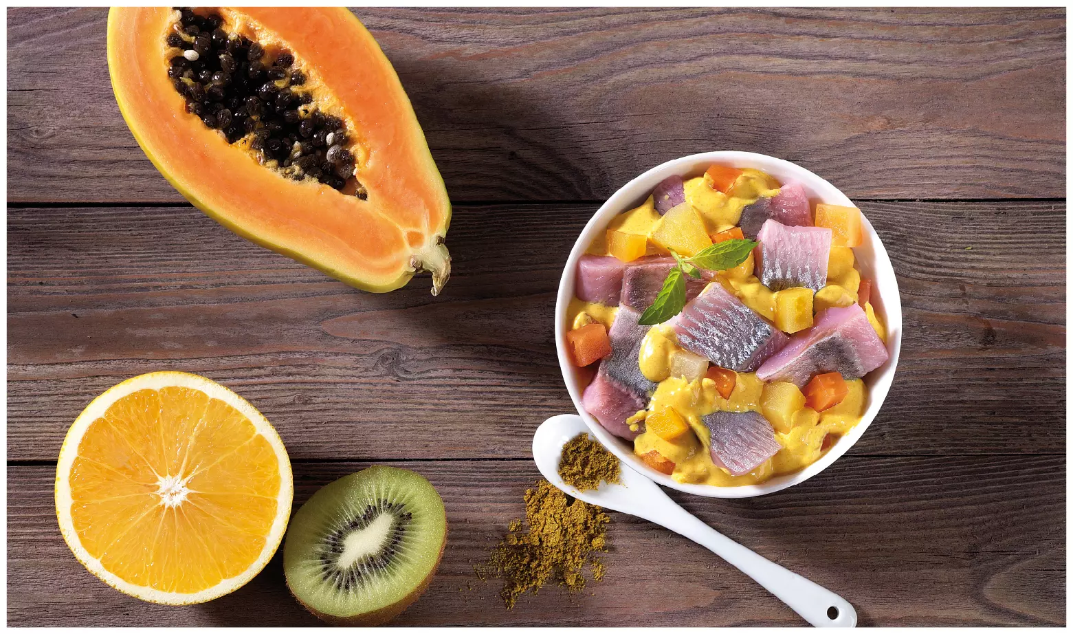 Schale mit Heringssalat, Papaya, Orange, Kiwi und Curry