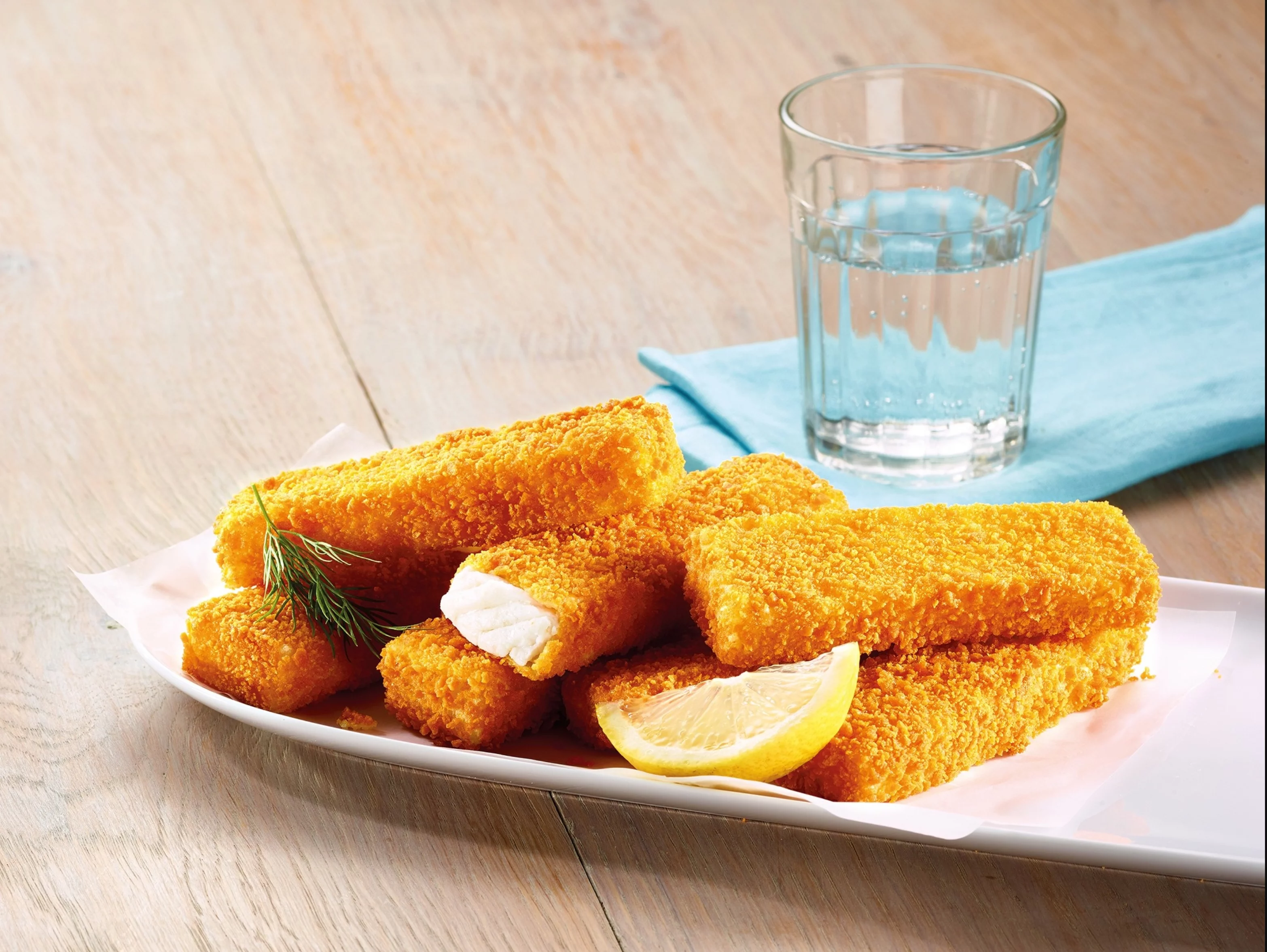 knusprige Fischstäbchen auf Teller mit Zitrone und Dill