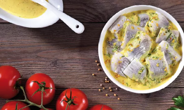 Matjesfilets in Senfsoße in einer weißen Schale mit frischen