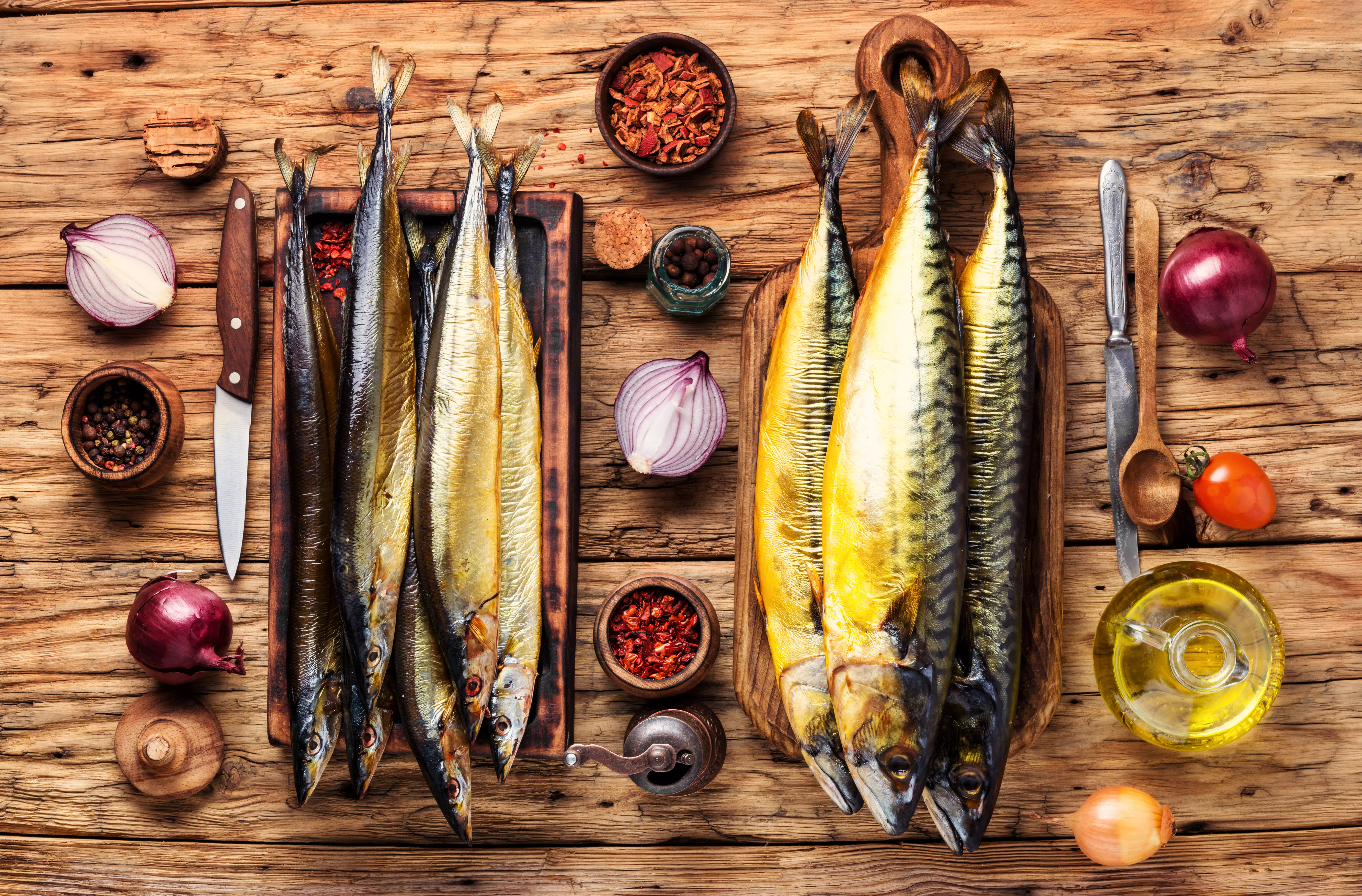 geräucherte Makrelen auf Holzbrett mit Zwiebeln und Gewürzen